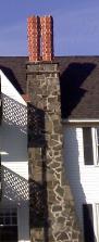 Stone chimney with brick flue extensions is restored, at The University of Southern Maine