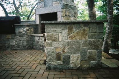 Outdoor stone kitchen with stone fireplace.